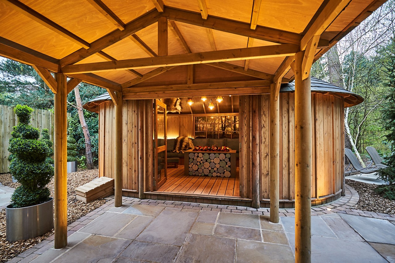 Scandinavian Snug with a central glowing fire nestled in the surrounding forest garden.